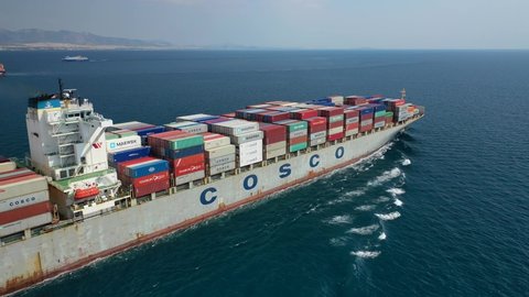 Piraeus, Attica - Greece - June 21 2020: Aerial drone video of fully loaded COSCO container tanker ship cruising near port of Piraeus
