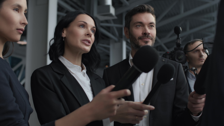 Business people at corporate event or official meeting. Interview of serious bank executive at press conference in office center for tv news. Political talk to microphones in hands of many journalists | Shutterstock HD Video #1070036182