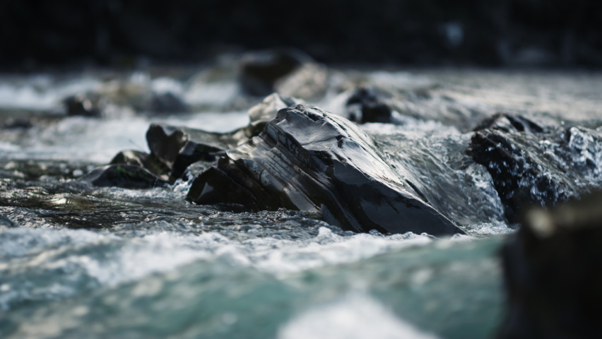 Clear stream running through stone boulders in carpathians. Abundant river flowing on stone bottom in slow motion. Wild mountain river water splashing in summer day.  Royalty-Free Stock Footage #1070038924