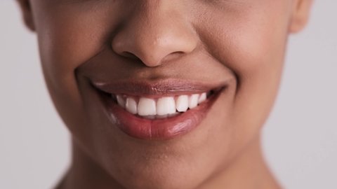 A close-up cropped view of a surprised woman's mouth isolated over a gray background in the studio
