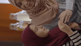 Muslim little girl in hijab and with her Muslim mother pray at home.Muslim mother and daughter pray together at home and then hug. Prayer concept.Video for the vertical story.