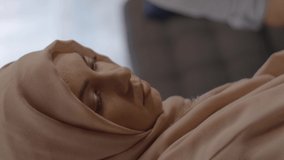 While the sad Muslim woman wearing a headscarf is looking sad with her eyes and she continues to feel sad despite her husband is giving comfort of her. Video for the vertical story.