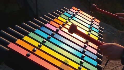 Playing the xylophone. A child's hand strikes the colorful keys of the xylophone.