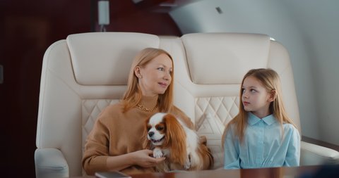 Flight attendant taking order from family in first class airplane interior. Mother, father, daughter and dog travelling on private jet and ordering breakfast