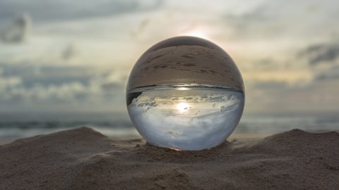 time lapse crystal ball placed on the beach at sunset. To see the sea upside down in a glass ball.

