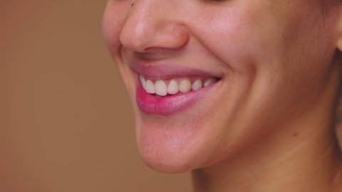 Beautiful female lips smiling revealing white teeth. Face of an African American woman with natural beauty. Close up macro portrait. Side view. Slow motion ready, 4K at 59.94fps.