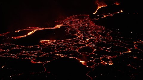 Iceland lava field with molten magma flowing as rivers on dark surface at night