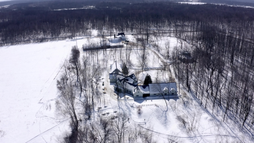 Aerial shot turning around a large chalet on a beautiful sunny winter day