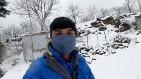Selfie video of an Indian man wearing mask enjoying the snowfall while following the new Covid Travel Guidelines at Manali in Himachal Pradesh, India