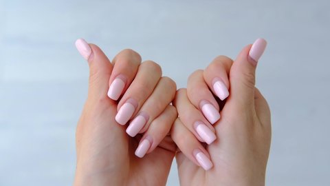 Female hands with old worn long lasting painted nails with  pastel pink gel polish cover.  Overgrown manicure. Time for correction gel polish. Nail care concept. Woman shows regrowth of her nails.