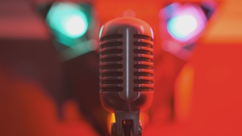 Retro vintage microphone on stage in nightclub on background of spotlight of color music close-up.