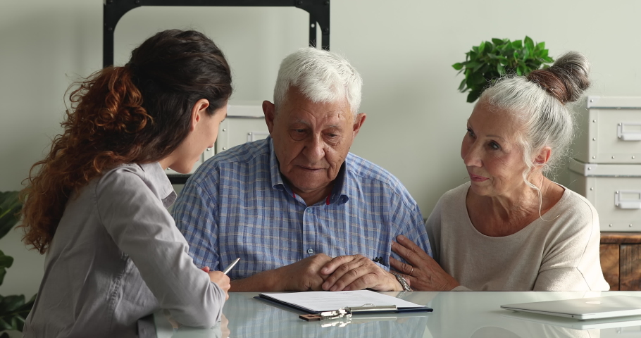 Professional young female real estate agent explaining house purchase contract details to older mature family couple, giving keys from own accommodation after signing agreement at office meeting. Royalty-Free Stock Footage #1070084788