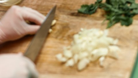 Cutting garlic with a knife. Chef's hands cuts the cloves of garlic in small pieces. Process of making salsa