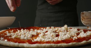 Chef is putting cheese onto piece of dough when making pizza. Cooker applying fresh ingredients while making italian pizza. food and drink 4k footage