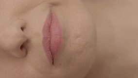 Close-up of beautiful young woman with beautiful lips biting her lips.Macro shot of human lips.Video for the vertical story.