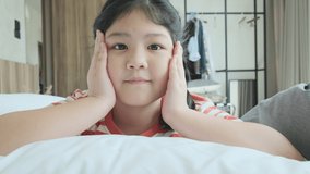 asian female child happy video calling conversation with her parents on white soft bed and blanket in bedroom,daughter video call with her remote family new normal lifestyle