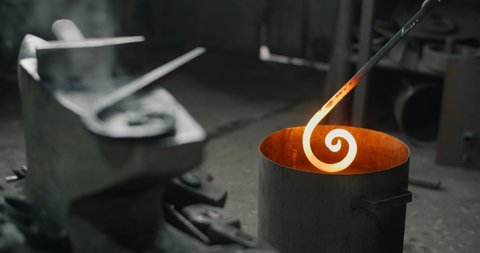 Blacksmith puts the red-hot forged metal part into the water with a lot of steam in slow motion, quench process, metalwork at workshop, 4k 60p Prores HQ