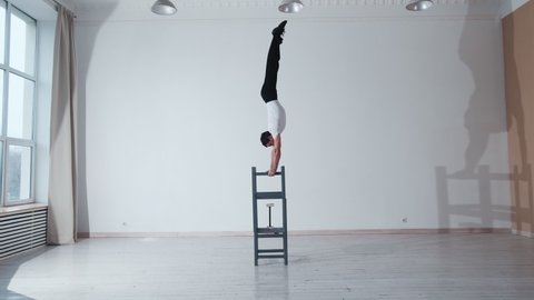 The acrobat keeps balance on the chairs. Acrobatic number without insurance