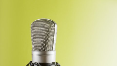 Studio microphone on an anti vibration stand rotating. Professional audio recording equipment on yellow to white background.