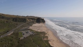 4K Aerial drone video of cliffside beach with waves and parking lot