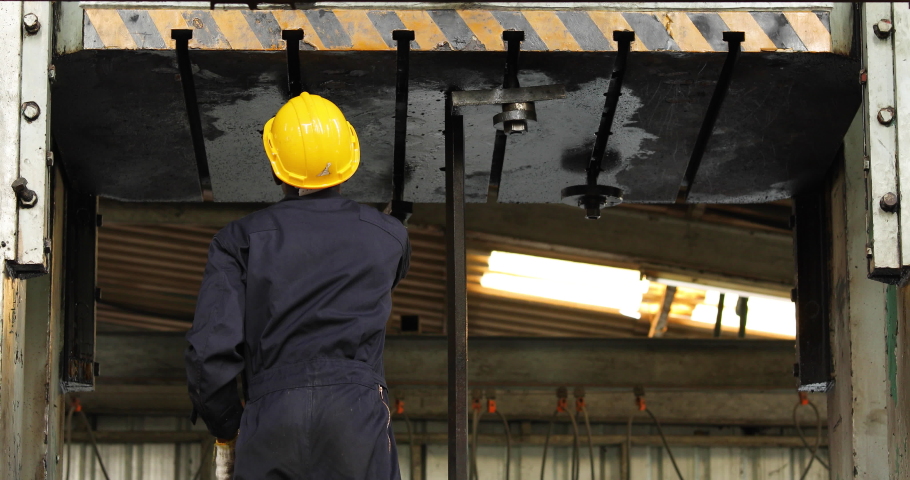 Young black male engineer checking checking and repair the machine in Heavy Industry Manufacturing Facility. Service and Maintenance of factory machinery. American African people.
