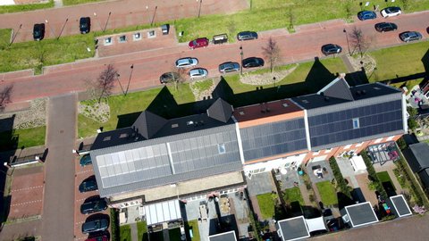 Aerial of solar panels on rooftop of house, drone pulling back and revealing solar panel filled neighbourhood