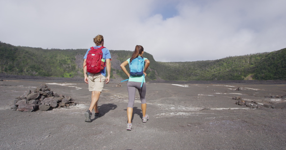 Couple tourists hikers walking on Kilauea Iki crater trail hike in Big Island, Hawaii. USA summer travel vacation destination for outdoor nature adventure, American tourism.