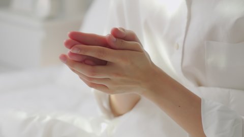 Close up of woman hand holding and applying moisturiser, Body lotion in bedroom.