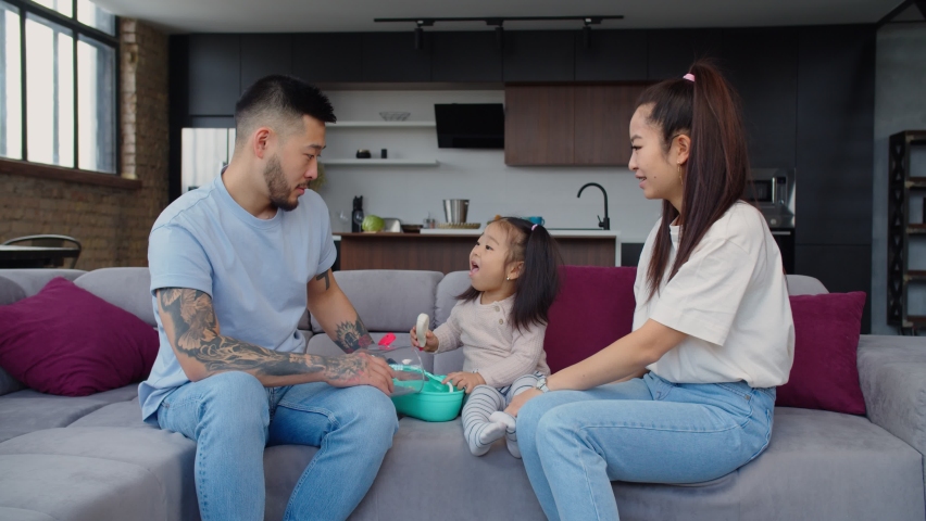 Happy positive asian cute toddler daughter and cheerful parents playing in doctor and patient using toy medical instrument, developing child through educational and cognitive game in home interior, Royalty-Free Stock Footage #1070139598