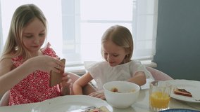 Children take selfies during a delicious breakfast or lunch. Two girls eat toasted bread with chocolate nut butter , fruits and berries. Slow motion 4K UHD video 50 fps