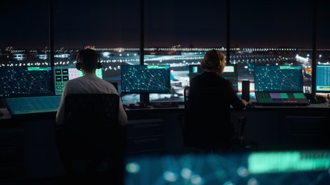 Diverse Air Traffic Control Team Working in Modern Airport Tower at Night. Office Room Full of Desktop Computer Displays with Navigation Screens, Airplane Departure and Arrival Data for Controllers.