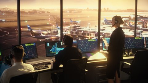 Female and Male Air Traffic Controllers with Headsets Talk in Airport Tower. Office Room Full of Desktop Computer Displays with Navigation Screens, Airplane Flight Radar Data for Controllers.