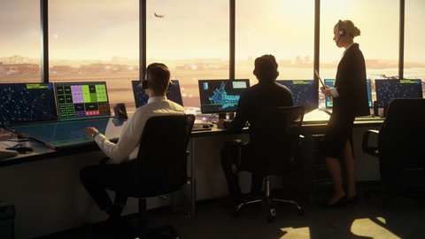 Diverse Air Traffic Control Team Working in a Modern Airport Tower at Sunset. Office Room is Full of Desktop Computer Displays with Navigation Screens, Airplane Flight Radar Data for Controllers.