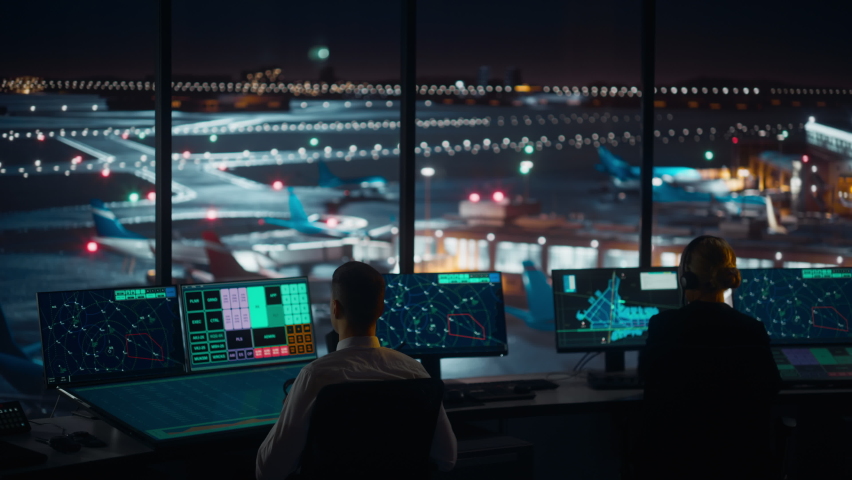 Diverse Air Traffic Control Team Working in Modern Airport Tower at Night. Office Room Full of Desktop Computer Displays with Navigation Screens, Airplane Departure and Arrival Data for Controllers. Royalty-Free Stock Footage #1070147677