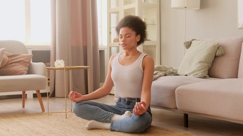 African american woman  meditating while sitting at home. Calm female taking deep breath and relaxing with eyes closed. No stress and peace of mind.