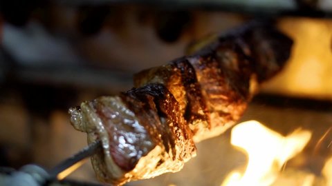 Picanha beef being grilled on open flame barbeque spit