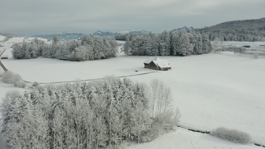 Aerial of small farmhouse in snow covered winter landscape