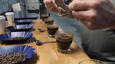 Spoons being rinsed during the coffee cupping test process, slow motion close up