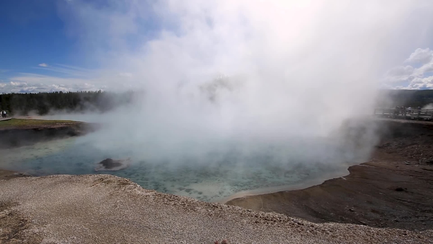 Stunning panning view across huge geothermal geyser with dense steam cloud rising at Yellowstone National Park, Wyoming, USA.