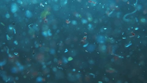 microplastics in water. plastic fragments or particles in ocean. ocean pollution by single-use plastics. environment, ecology, water, earth, slow motion