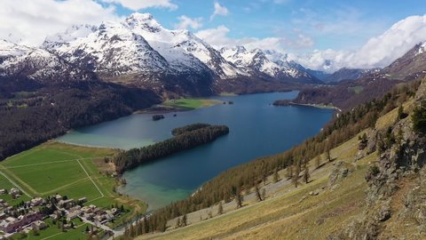 Dramatic aerial footage of lake Sils near Silvaplana in the Engadine valley in Canton Graubunden in the alps in Switzerland on a sunny summer day with Piz Corvatsch in the background