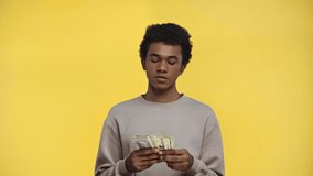 african american teenager counting money isolated on yellow