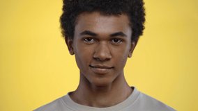 african american teenager smiling at camera isolated on yellow