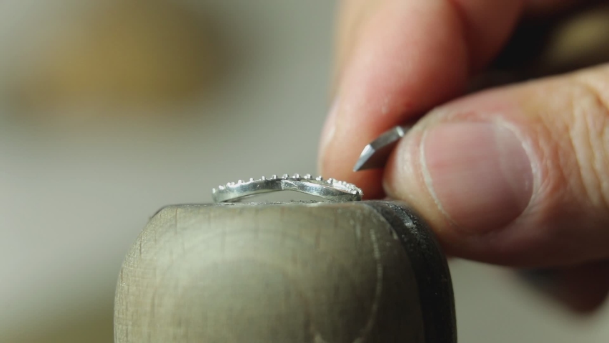 Goldsmith creating white golden accessory and putting precious crystal diamonds on the jewelry . Expensive jewelry making process . Shiny brilliant stones . Beautiful design of precious metal