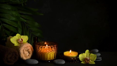 Spa composition with burning candles, zen stones, flowers. Wellbeing, relax massage and body treatment concept.