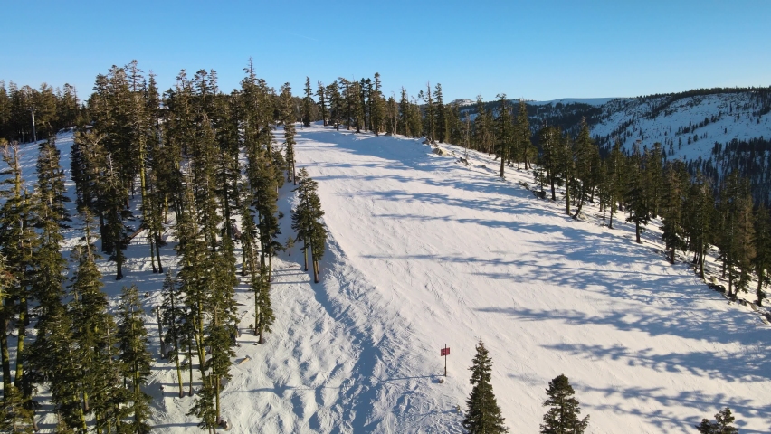 Aerial view and pan shot over ski slopes, trees and chair lift in Tahoe. No people