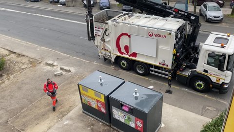 Paris Suburb, France - 5 April 2021 - Modern garbage truck collecting recyclable and non recyclable waste with minimal human help, using the truck equipped with hydraulic pistons and cylinders.