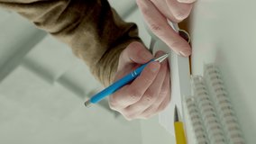 Close-up of hands writing in a notebook. The man at his desk writes with a pen. Vertical video.