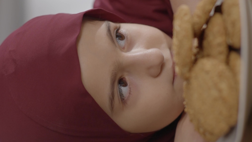 A Muslim little girl is happy looking at milk and cookies.Milk and cookie love concept.Video for the vertical story.