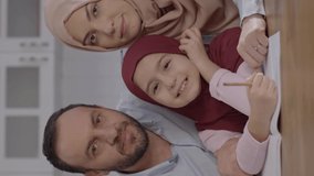 Young Muslim couple helping the boy with lessons at home.Happy and beautiful Muslim family are smiling at the camera. Portrait of a happy and beautiful family.Video for the vertical story.